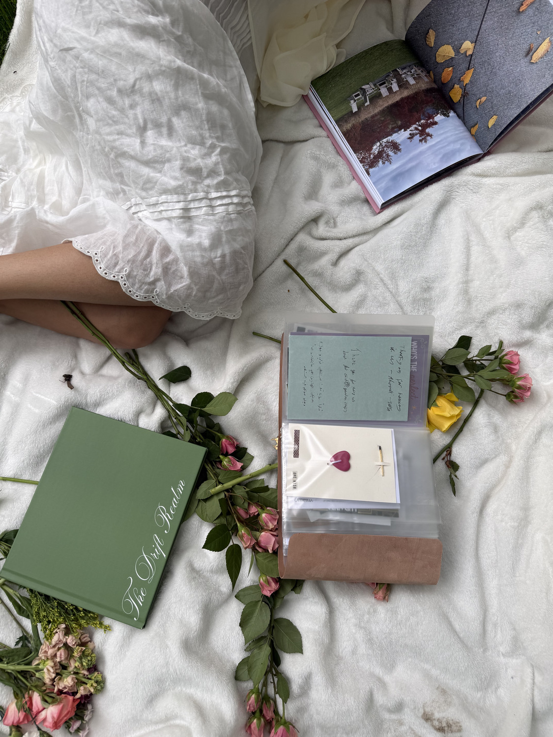 The Drift Realm and the leather journal open with handwritten notes, beside fresh flowers